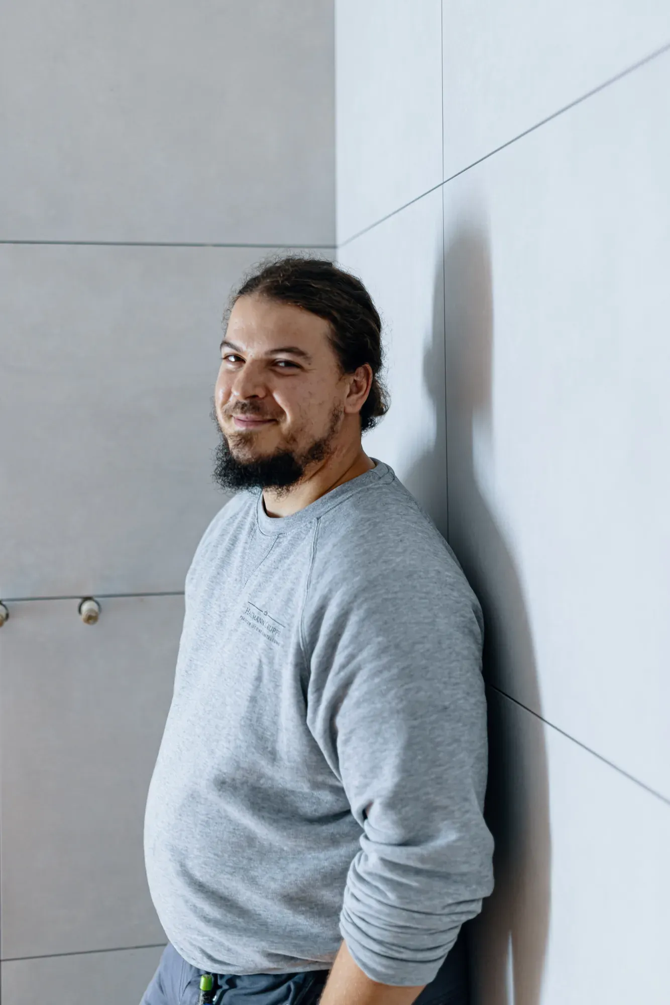 Patrick Hartmann lehnt lächelnd an einer frisch gefliesten Wand auf der Baustelle