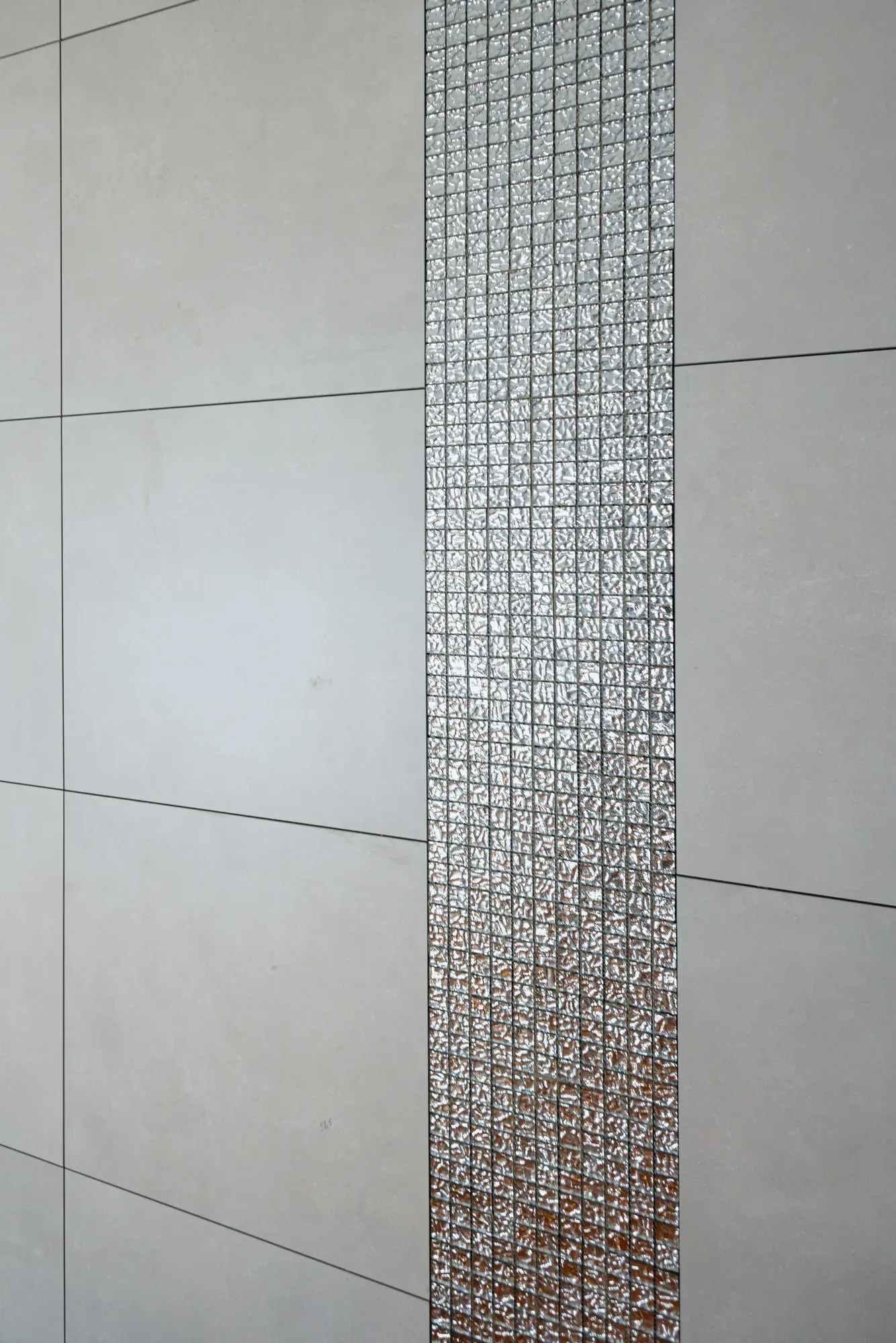 Großformatfliesen mit Mosaikstreifen an einer Badwand