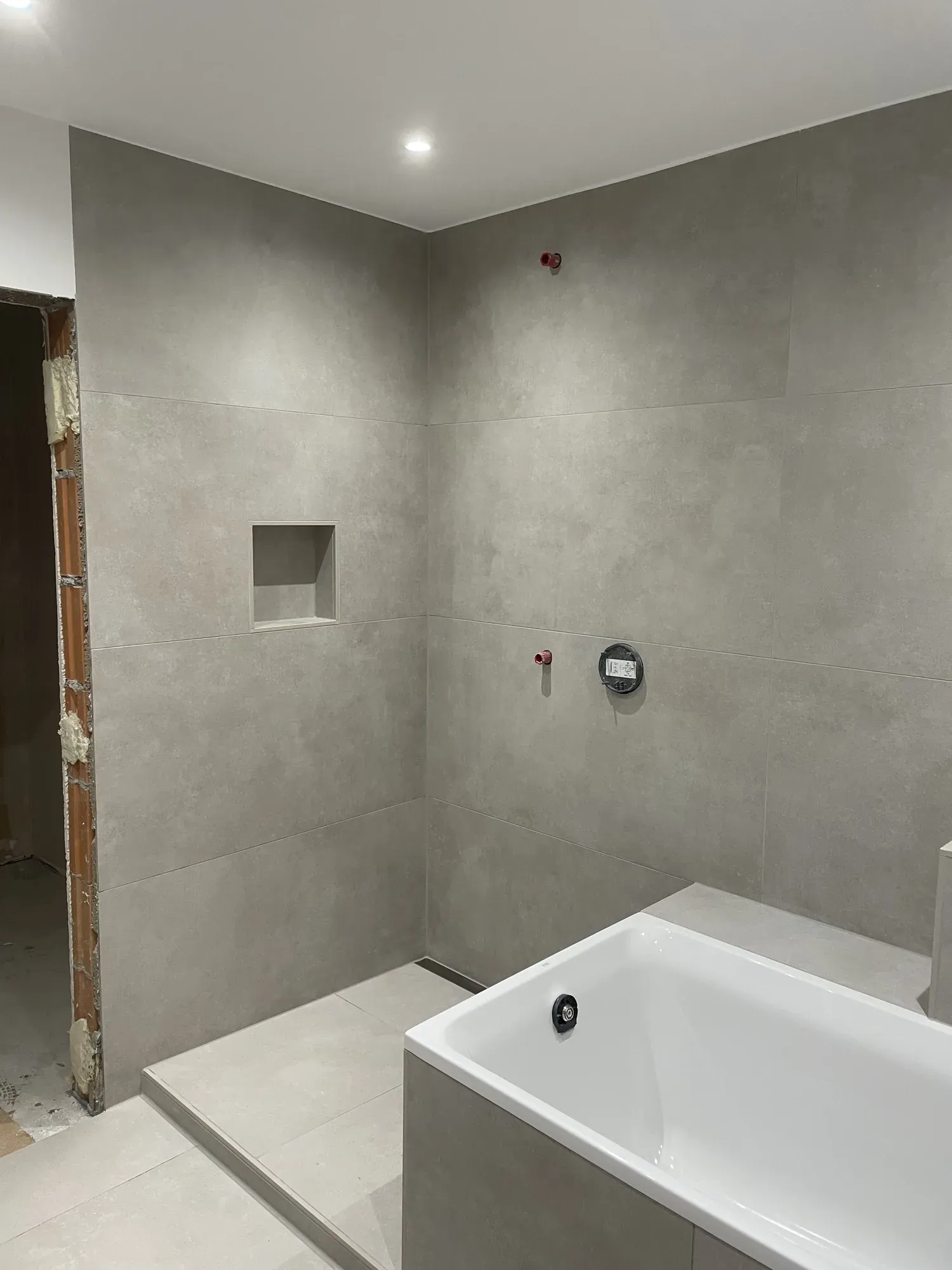 Saniertes Bad mit Wand und Wannenverkleidung in Betonoptik