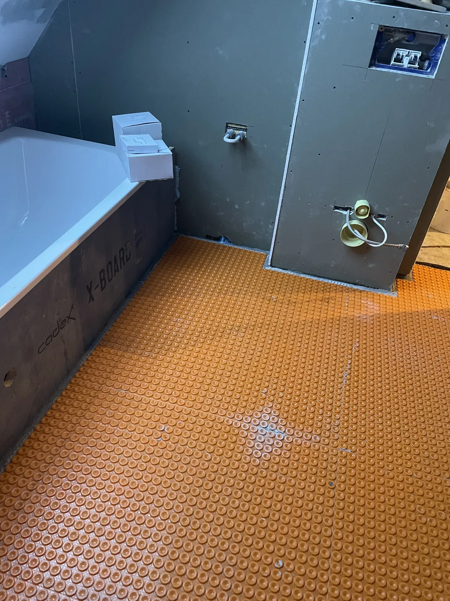 Zementgebundene Bauplatten an der Wand und Entkopplungsmatte auf dem Boden