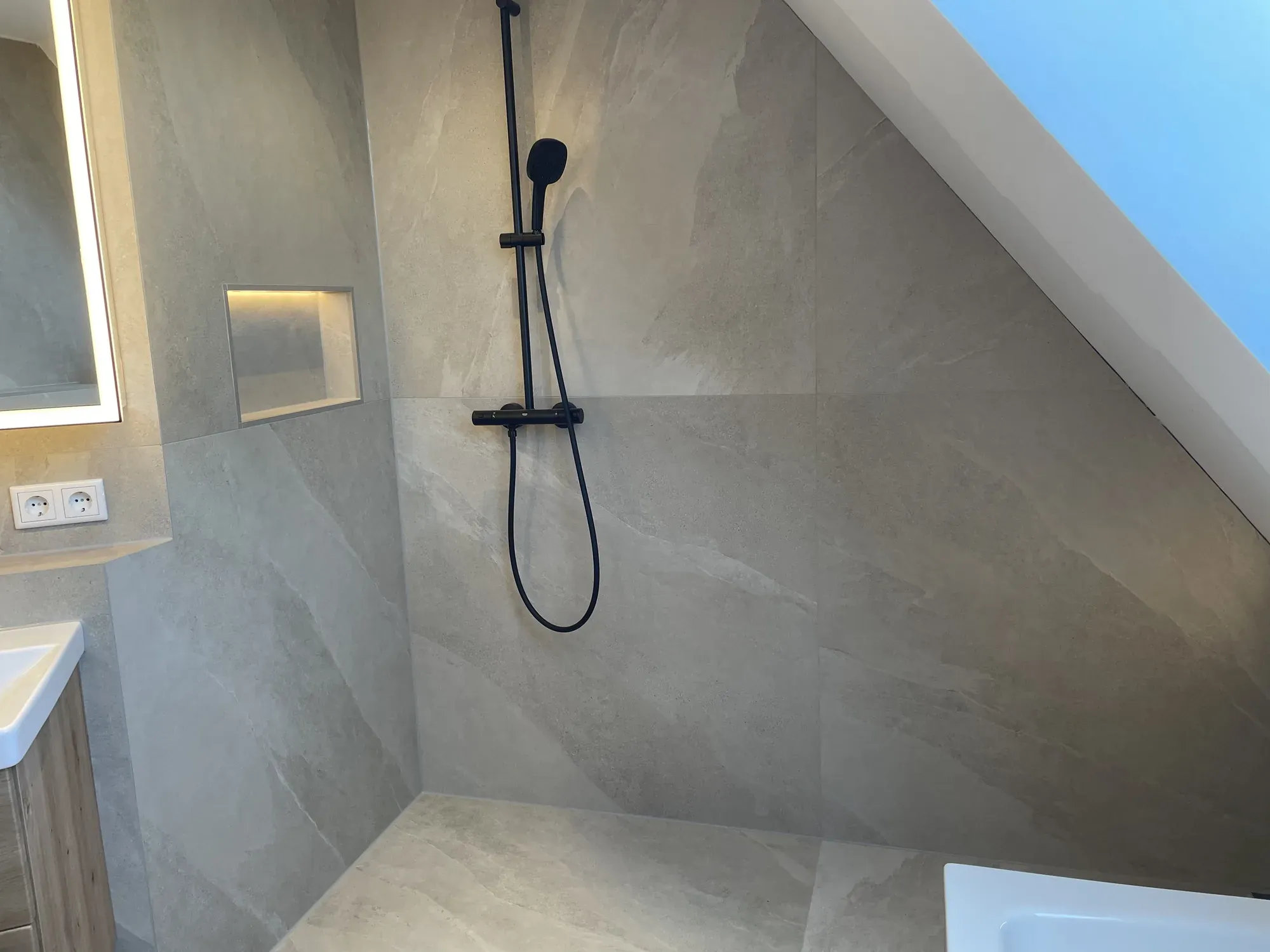 Dusche mit schwarzer Armatur, Handbrause und beleuchteter Nische