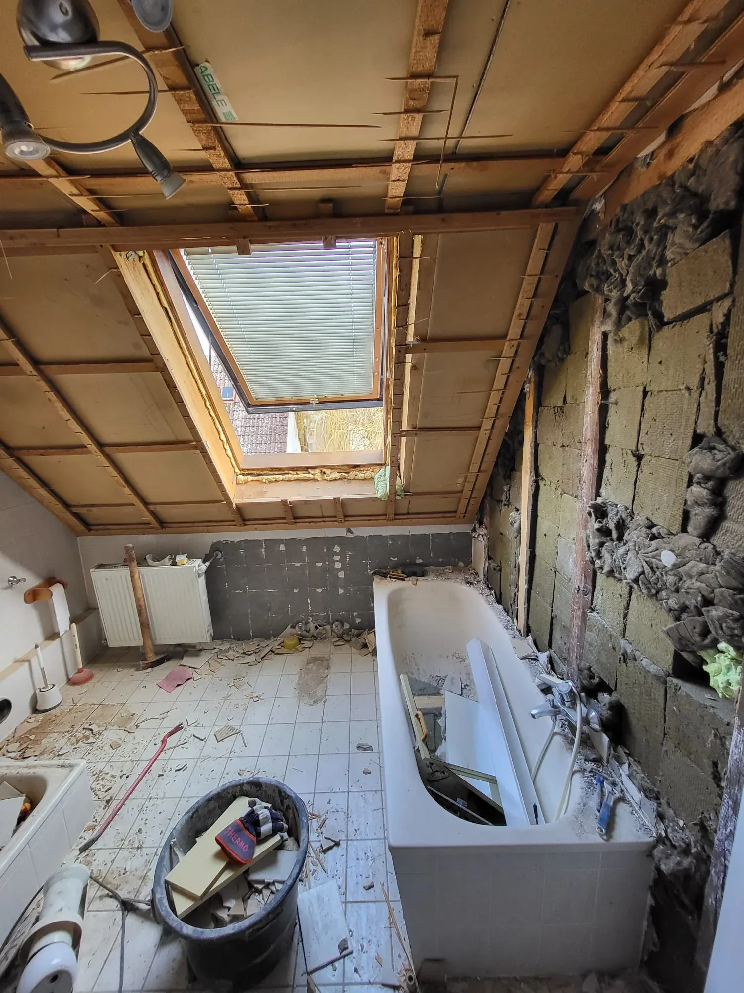 Entkerntes Dachbad mit freigelegten Sparren, Dachfenster und alter Badewanne