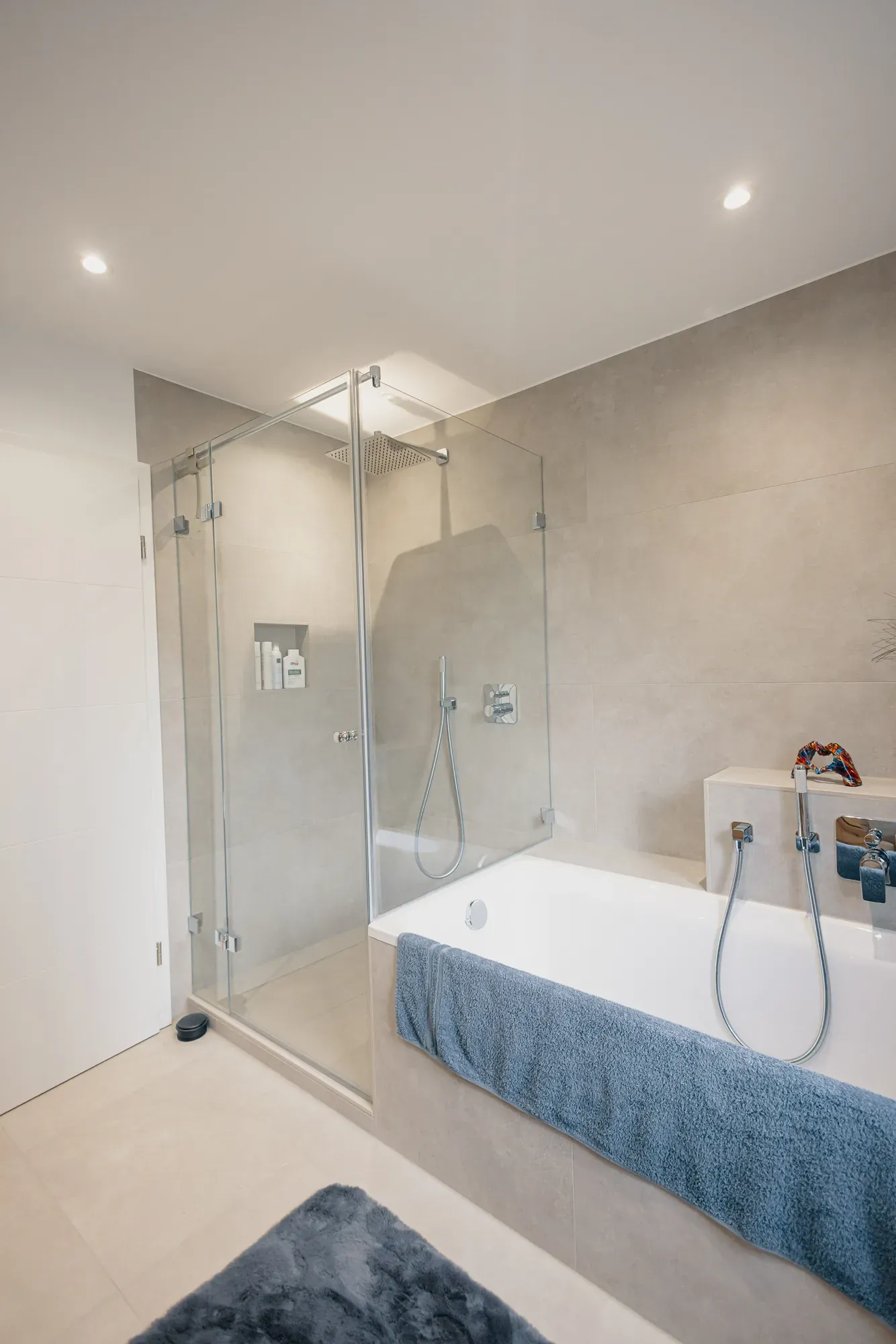 Glasdusche mit Regenbrause neben der Badewanne