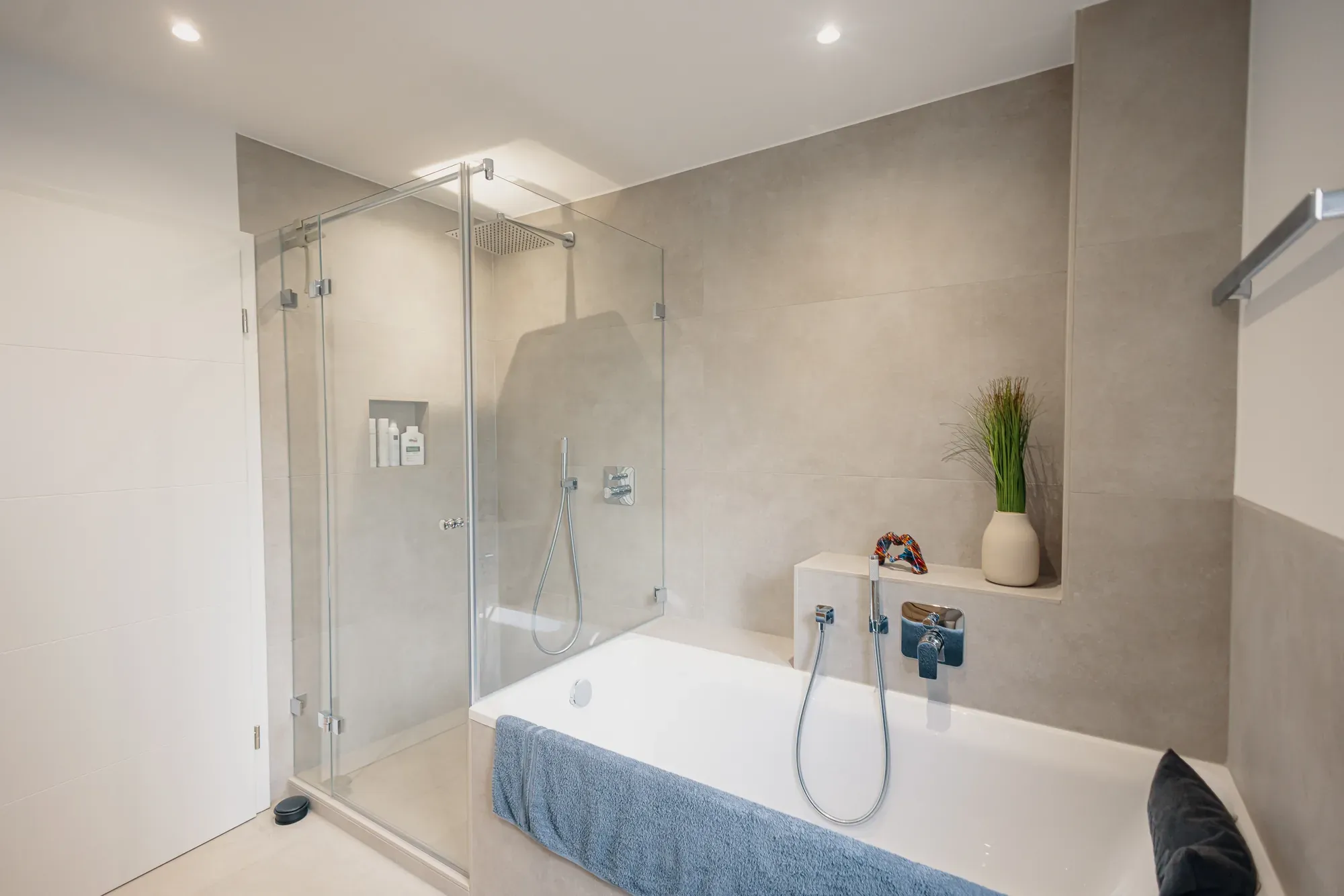 Fertiges Bad in Betonoptik mit Glasdusche, Badewanne und Ablage, saniert von der Hartmann Gruppe