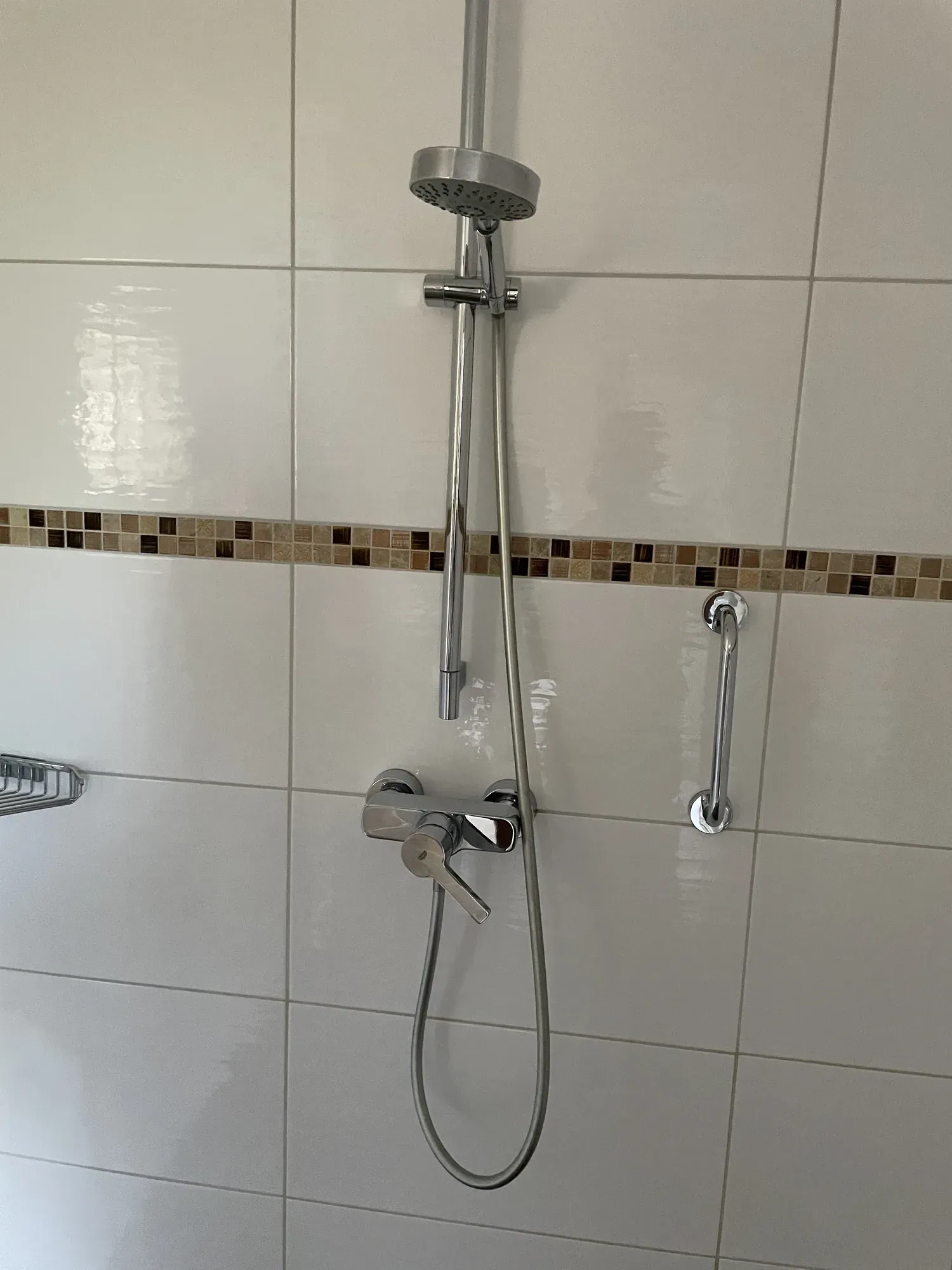 Dusche mit weißen Fliesen, Mosaikbordüre und Duschstange