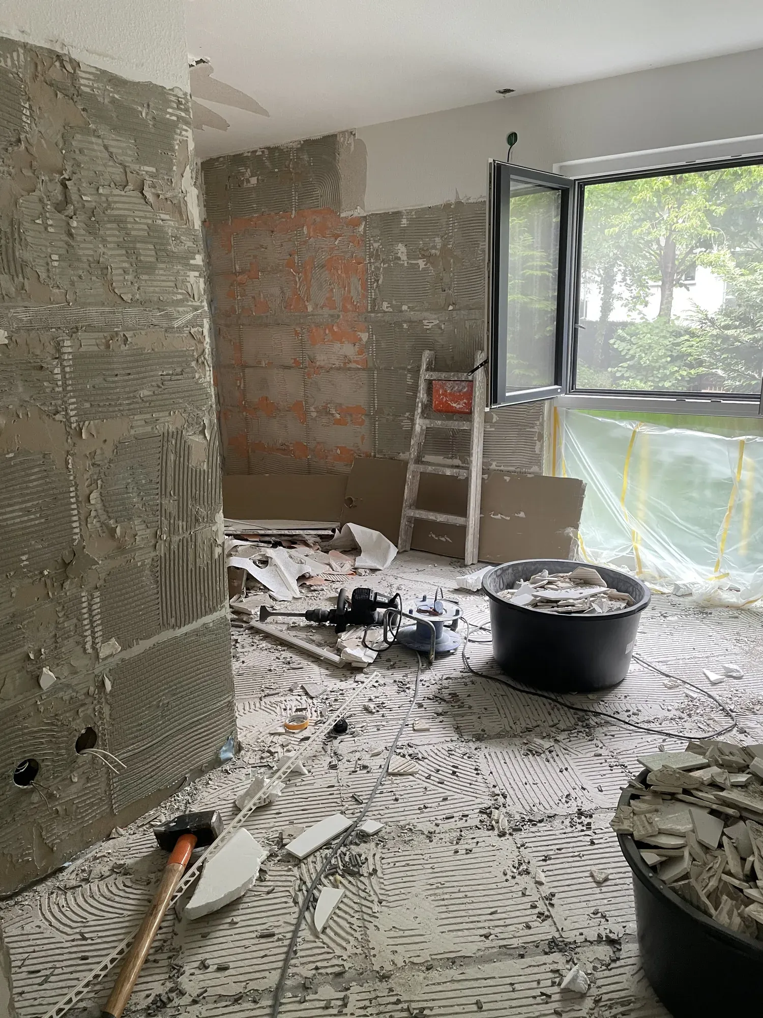 Entkerntes Bad mit Bauschutt, Mörtelkübeln und freigelegtem Mauerwerk