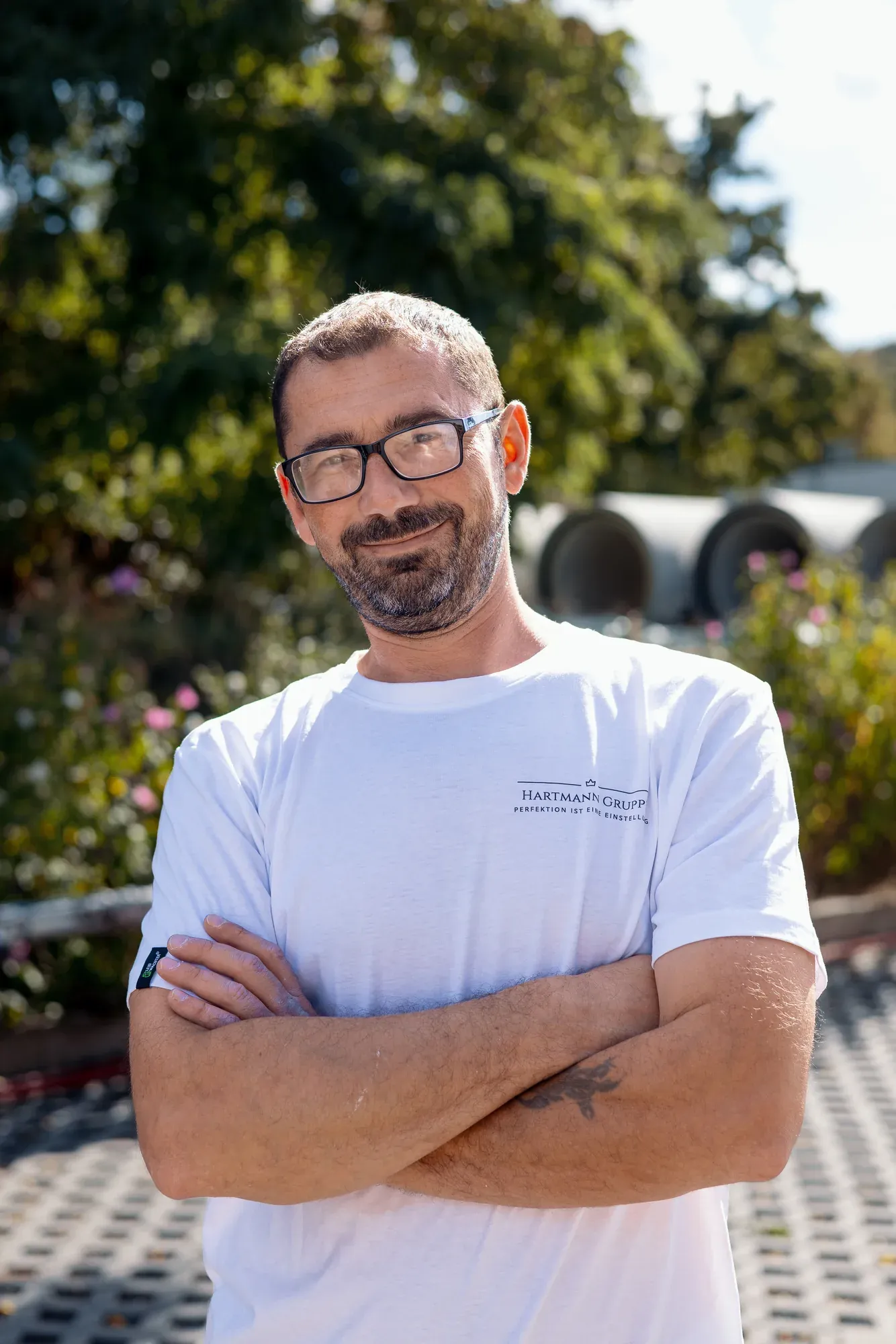 Mitarbeiter der Hartmann Gruppe mit Brille im weißen Firmenshirt